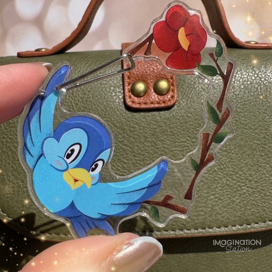 Blue bird-shaped pin on a green textured surface with 'Imagination Station' branding.