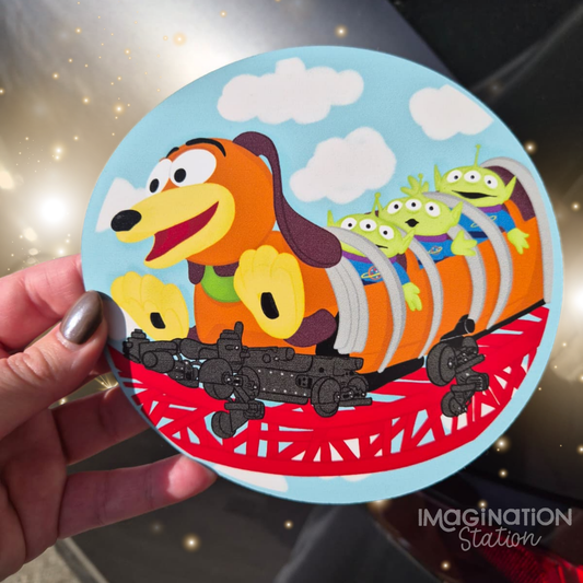 Circular toy with cartoon dog and aliens design, held by a hand.