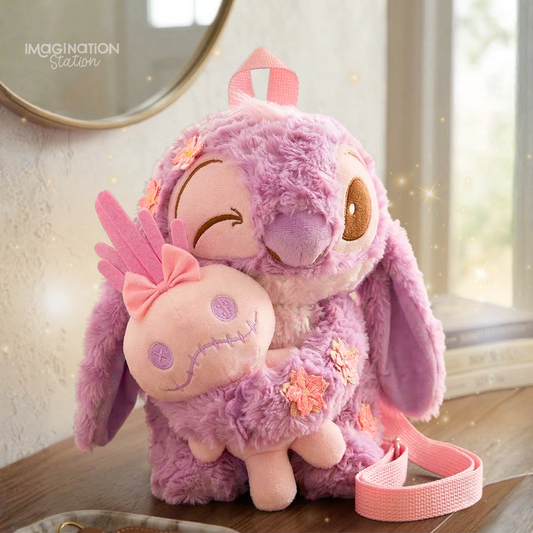 Two purple plush toys with pink accents on a wooden surface, with 'Imagination Station' branding.