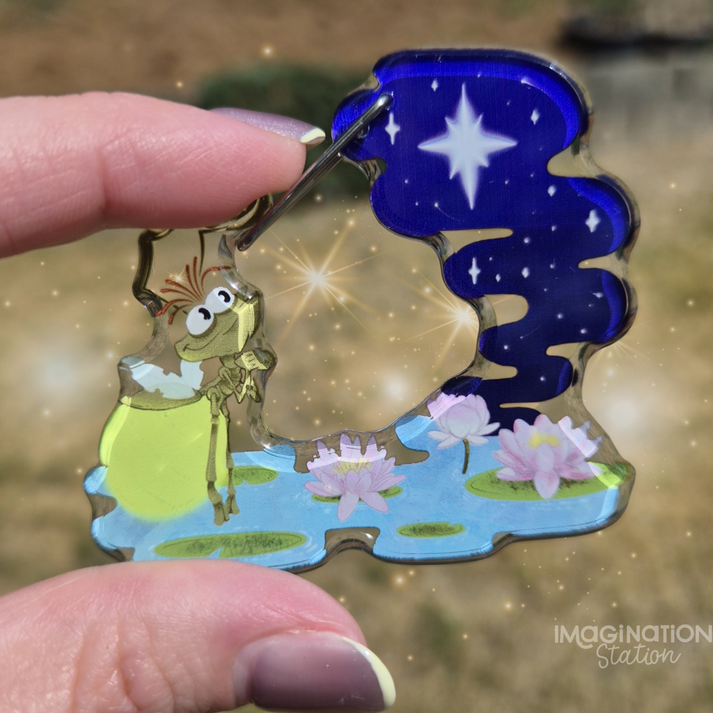 Colorful keychain with a character and nature design held by a hand.
