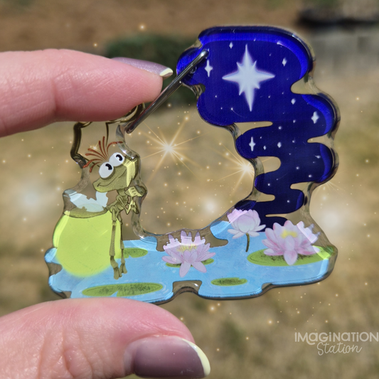 Colorful keychain with a character and nature design held by a hand.