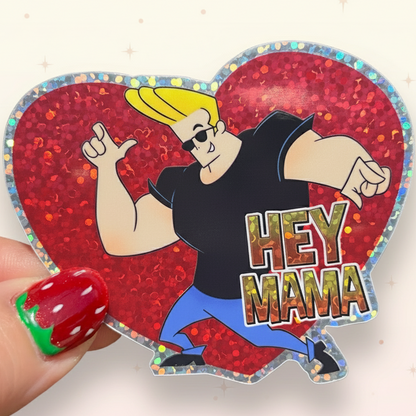 Heart-shaped glittery sticker with an animated character and 'HEY MAMA' text, held against a green leafy background.