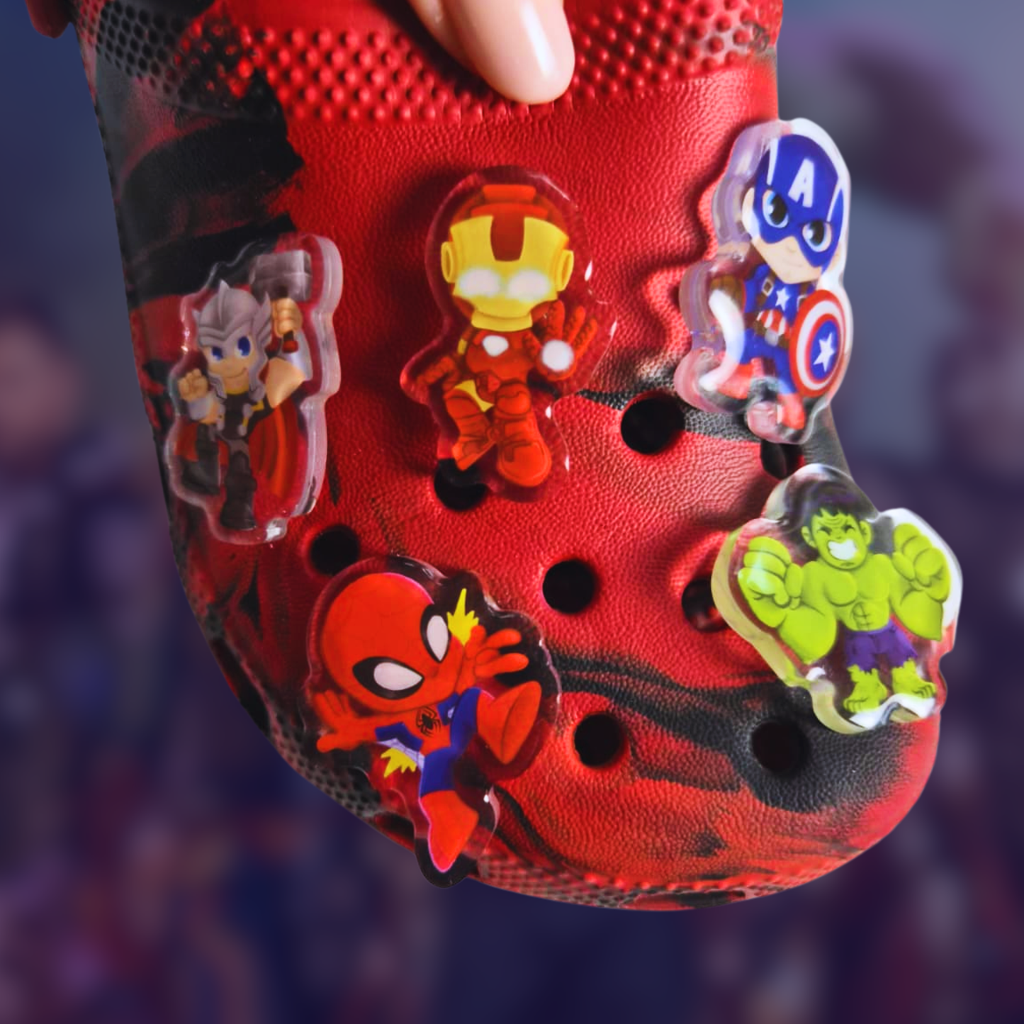 Red children's shoe with superhero character charms on a blurred background