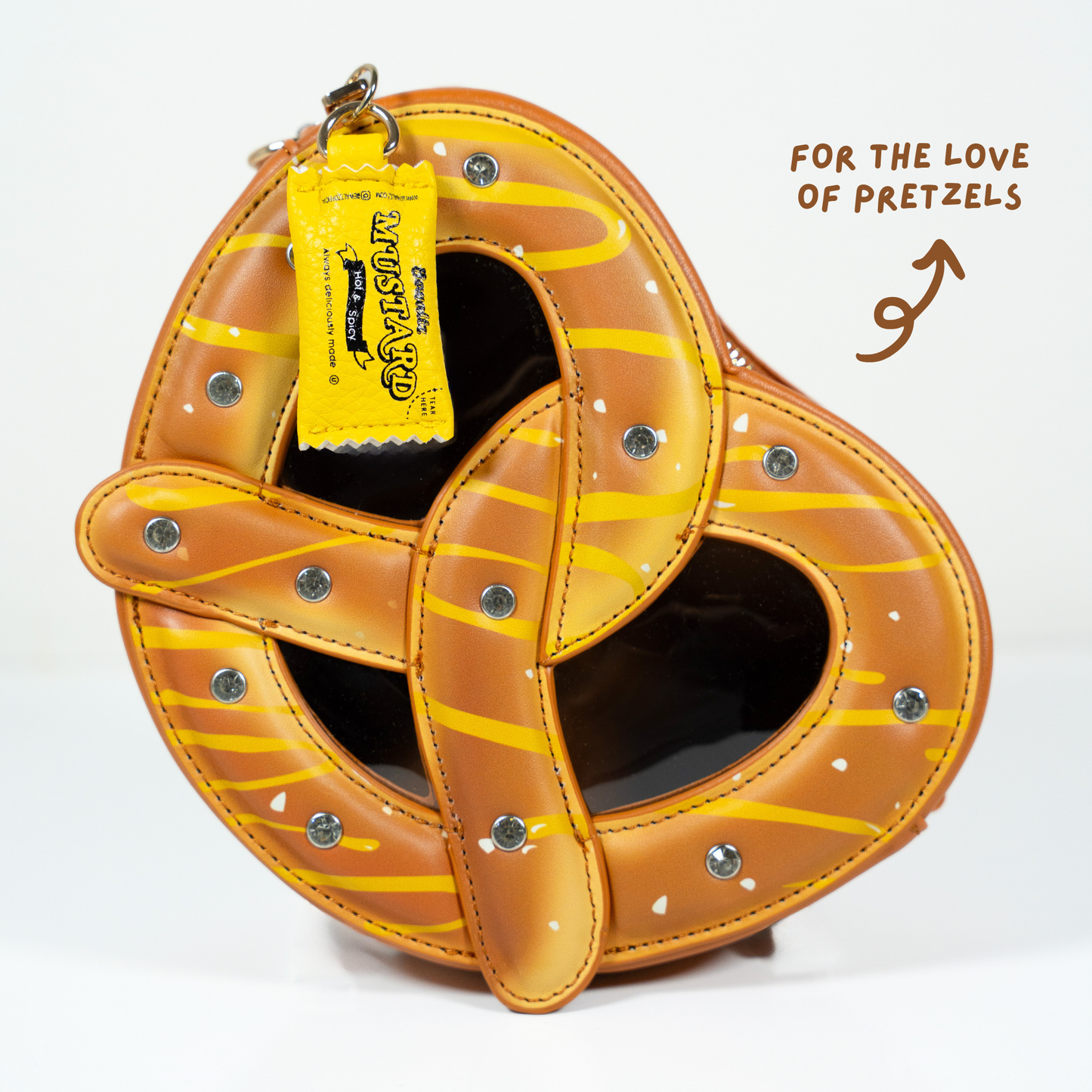 Pretzel crossbody bag close up showing mustard charm tag detail