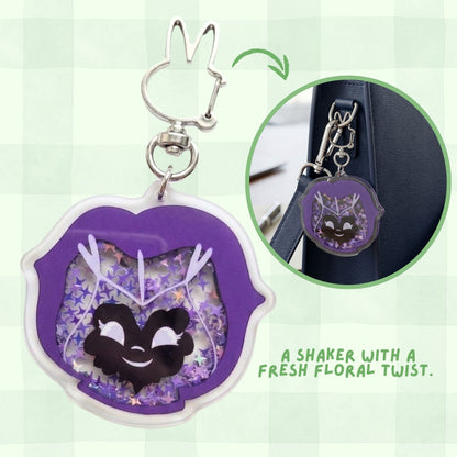 Keychain shaker with a cat design and floral elements on a green background