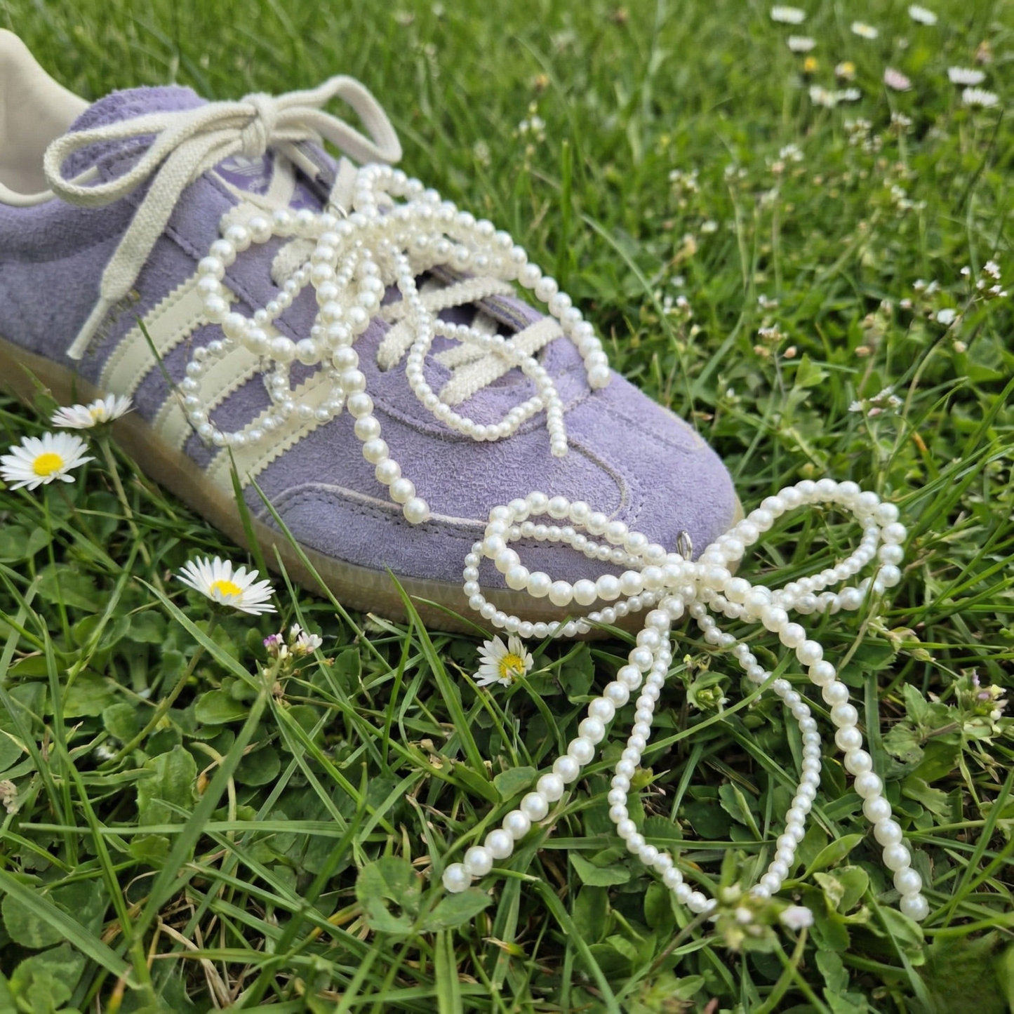 Purple sneaker with pearl-laced shoelaces on grass