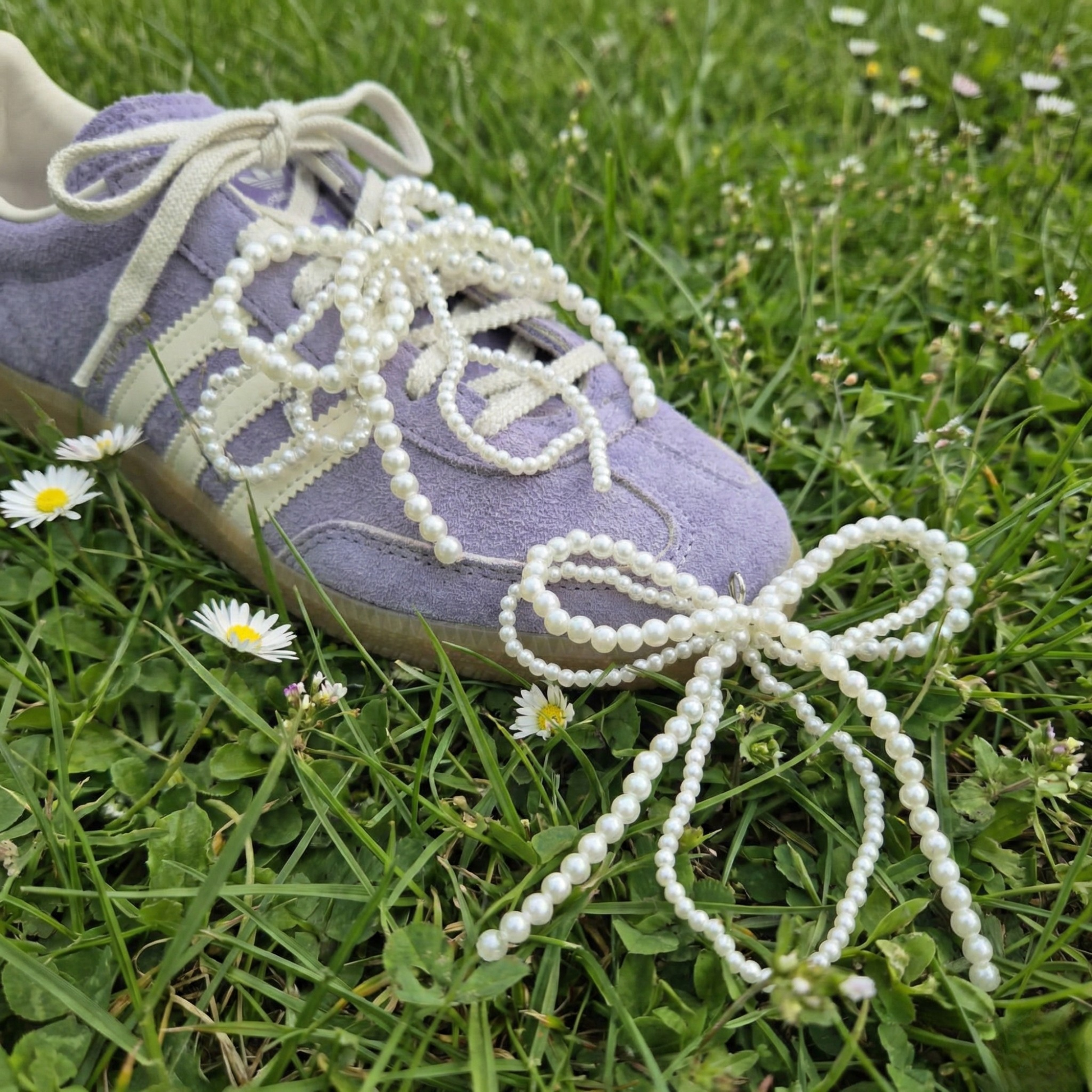 Purple sneaker with pearl-laced shoelaces on grass