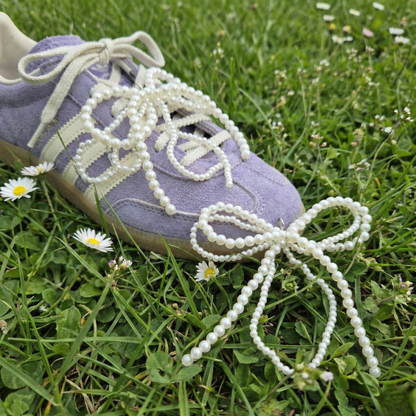Purple sneaker with pearl-laced shoelaces on grass