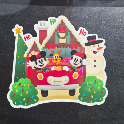 Christmas-themed sticker with Mickey Mouse, Minnie Mouse, and a snowman on a black surface