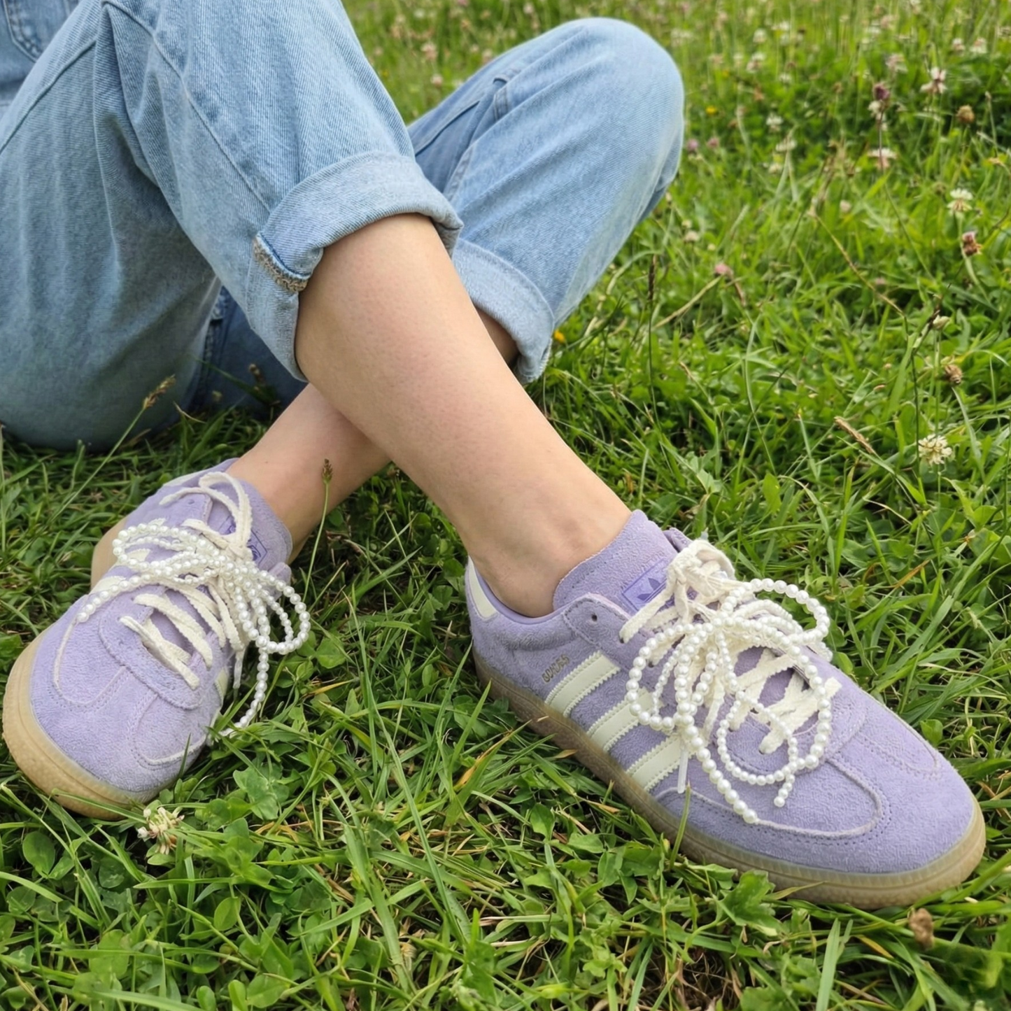 Person wearing purple sneakers with white laces on grass