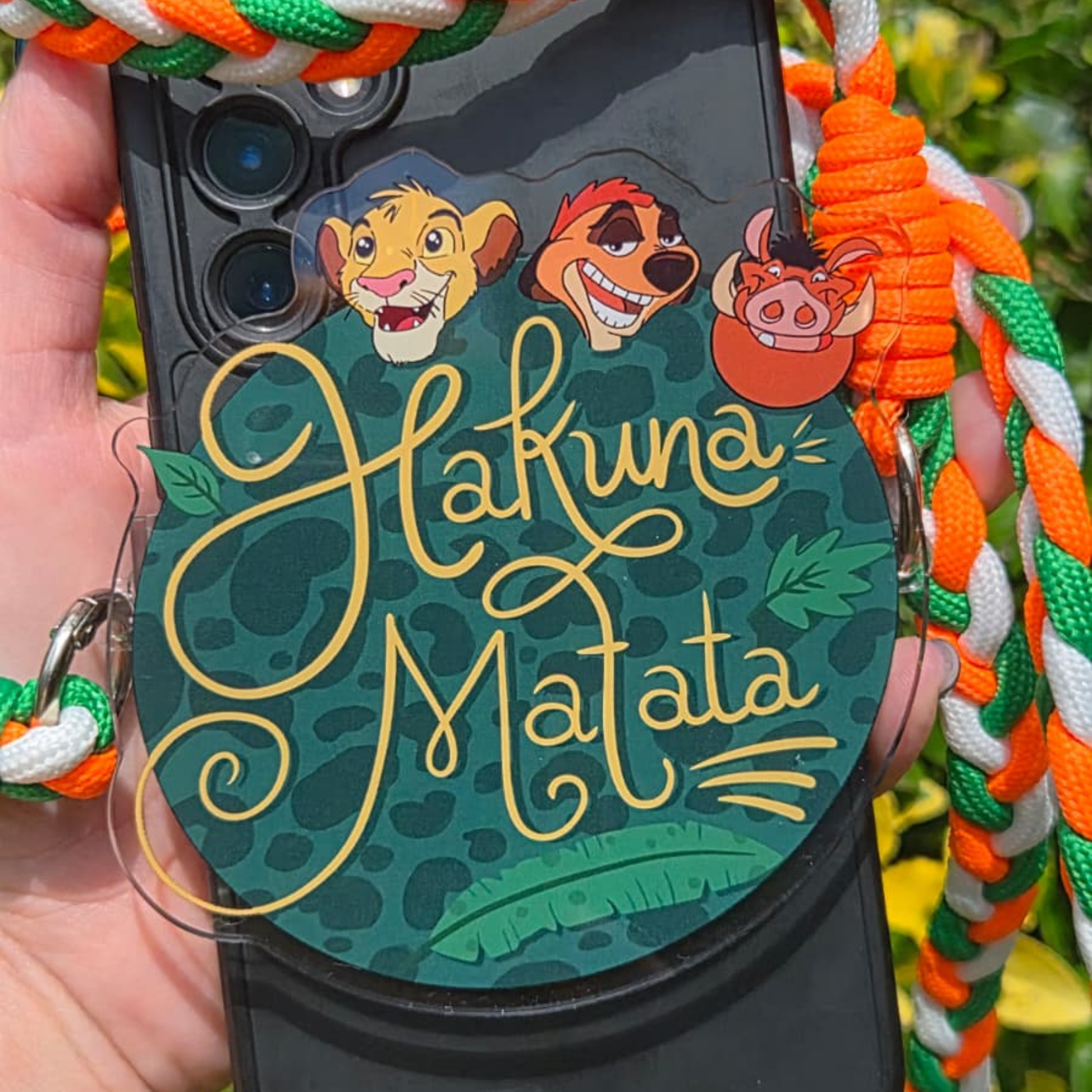 Hakuna Matata phone charm with braided orange green and white lanyard clip attached