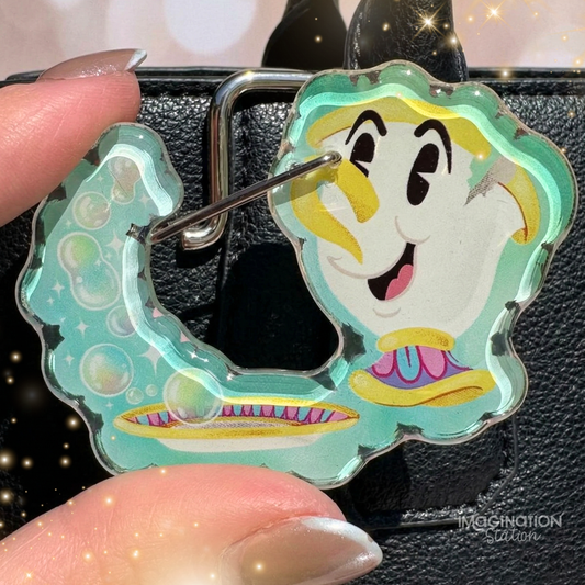 Cartoon character keychain held by a hand with a black background