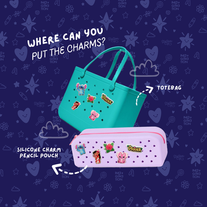 Teal tote bag and pink pencil pouch with charms on a dark blue background with cartoon designs.