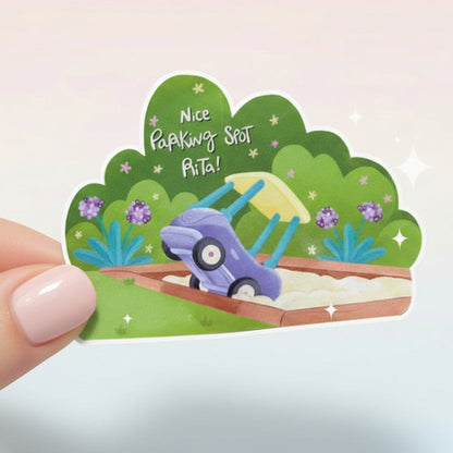 Hand holding a small decorative sign with a cartoon car and text on a white background
