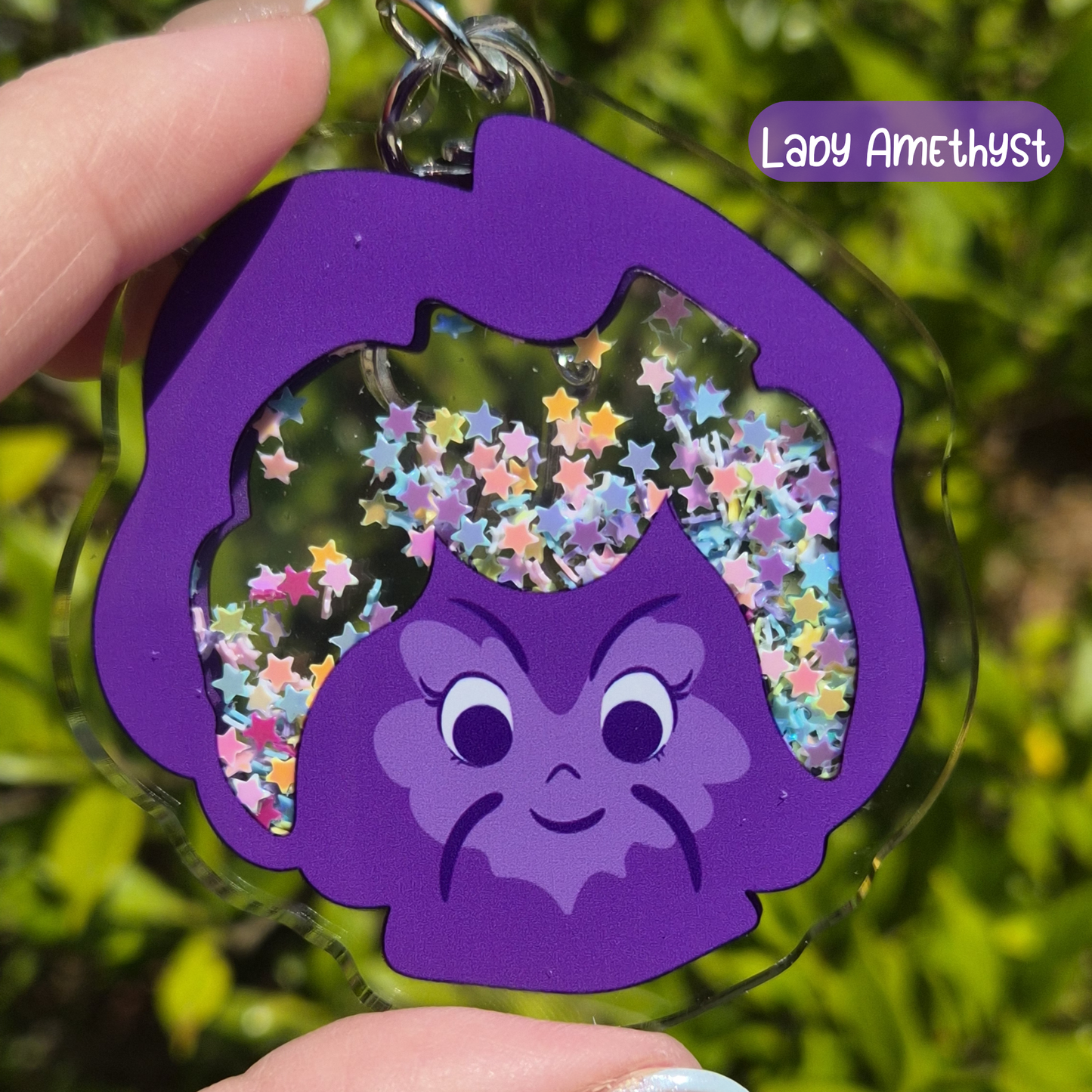 Purple character keychain with star-shaped cutout against a green leafy background