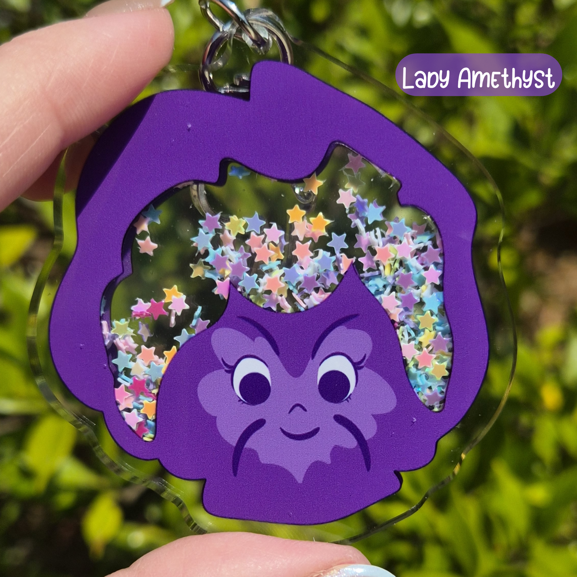 Purple character keychain with star-shaped cutout against a green leafy background