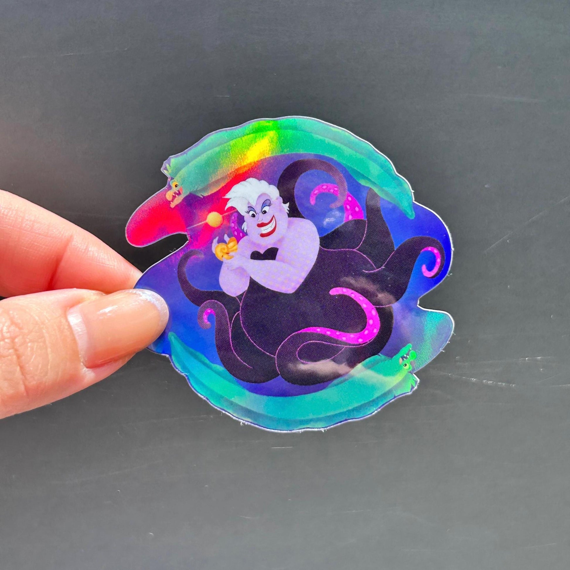 Holographic sticker of a character with a hand holding it against a dark background