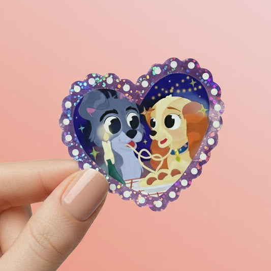 Sticker design of Lady and the Tramp with a heart shape on a pink background, featuring the text 'Lady and the Tramp Sticker' and 'Imagination Station'.