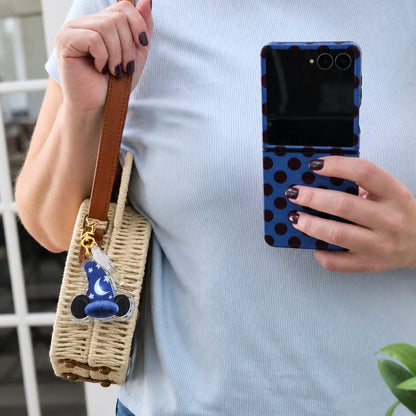 Woman holding a phone with a blue case and a woven bag, wearing a light blue t-shirt.