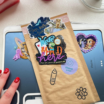 Alice in Wonderland We're Mad Here sticker held by hand – 3 x 2 inch glitter glossy vinyl