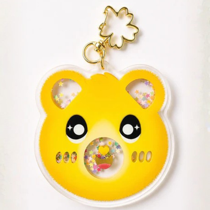 A yellow bear-shaped acrylic keychain charm with a gold flower clasp, featuring cute black eyes, colorful star-shaped shaker windows, and small decorative details on a plain white background.
