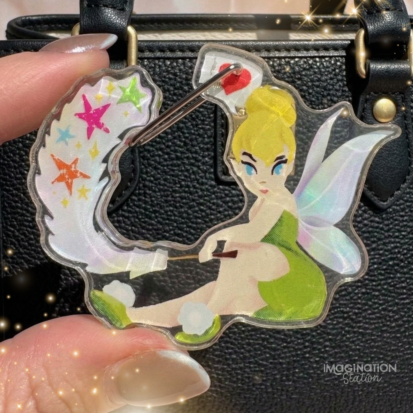 Transparent keychain with a fairy design held by a hand against a black textured background.