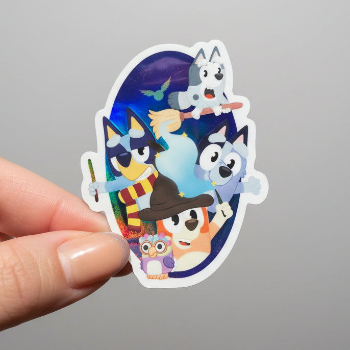 Hand holding a colorful sticker with cartoon characters against a blurred natural background