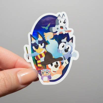 Hand holding a colorful sticker with cartoon characters against a blurred natural background