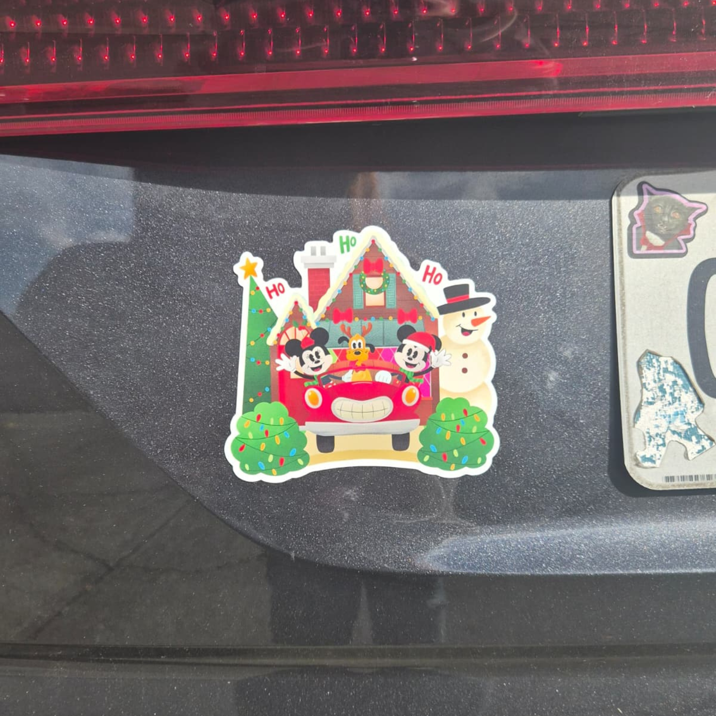 Christmas-themed car sticker with cartoon characters on a vehicle's rear window.