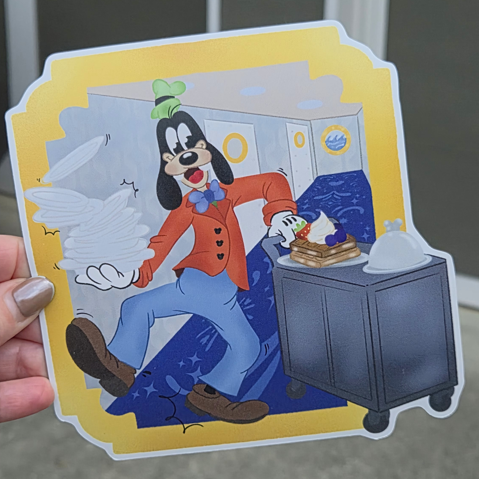 Close-up of custom die-cut Goofy waiter Disney cruise stateroom door magnet held by a hand